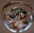 Two people stand under retail surveillance mirror.