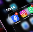 Closeup of a smartphone screen displaying the meta app group folder containing facebook, instagram, and whatsapp icons with notification badges.