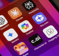Assorted AI apps are seen on an iPhone, including ChatGPT, Claude, Perplexity, Gemini, Microsoft Copilot, You.com, Suno, Character.AI, and Hugging Chat