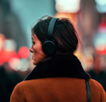 Woman wearing headphones in city at night.