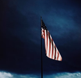 A drooping American flag amid a dark sky.