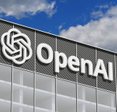 OpenAI logo on a gray corporate building against a blue sky