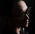Moody fashion portrait of a man in sunglasses on a dark background.