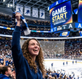 Woman cheering and waving a scarf at an indoor hockey game crowded arena