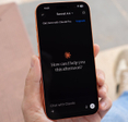 Hand holding cell phone with a new Claude chat opened on the screen.