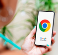 Woman with blue nails holding smartphone displaying Google Chrome logo