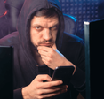 A man rubs his chin as he browses his phone.