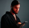 Bearded man in red lighting using a smartphone.