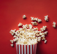 A box of popcorn laying on the red ground.