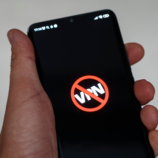 Man holding phone that shows the word "VPN" crossed out because it's been banned.