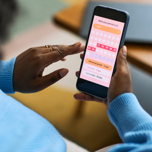 Woman using smartphone to track menstrual cycle.