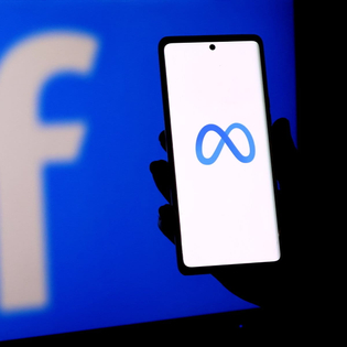 A person holding a smartphone displaying the meta logo in front of a facebook logo screen.