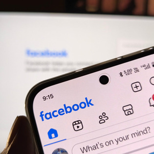 Smartphone showing facebook application interface on a blurred background.