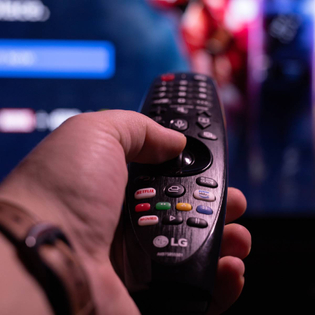 closeup of hand holding an LG smart TV remote