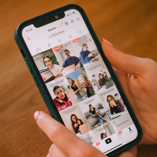 A well-manicured pair of hands holds a phone open to TikTok.