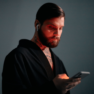 Bearded man in red lighting using a smartphone.