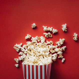 A box of popcorn laying on the red ground.