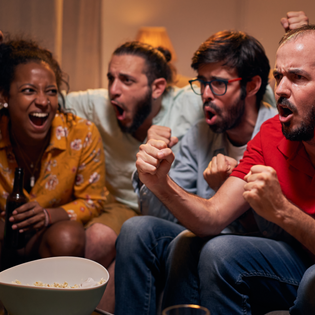 A group of friends are cheering and watching a game on TV.
