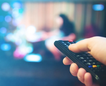 Image of remote being held up to TV