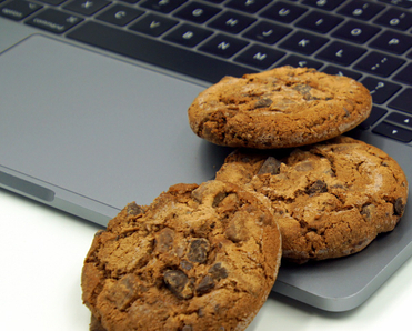 chocolate chip cookies sitting on a laptop keyboard