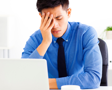 Man sitting in front of a laptop looking stressed