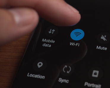 A close-up photo of a man&#x27;s fingers touching the Wi-Fi button on his cell phone.