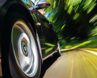 A close-up of the front of a black sports car as it speeds past, signifying increased internet speeds.