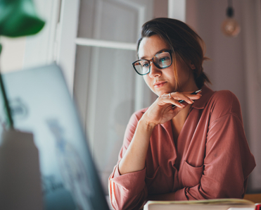 A woman sits at her desk and looks at her laptop. If she&#x27;s using public Wi-Fi, she should check to make sure her VPN is working.