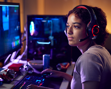 A young woman is playing a video game on her desktop computer.