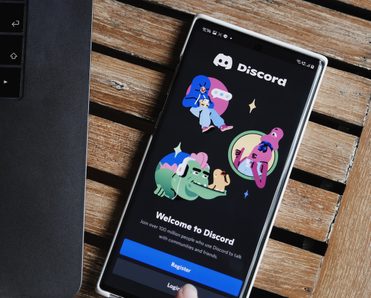 A laptop sits next to a cell phone that&#x27;s displaying the Discord welcome message.
