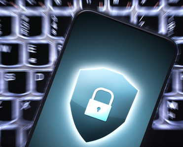 Blurry keyboard lit in the background and phone on top with security lock emblem on the screen