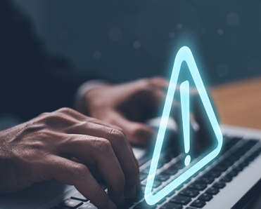 man&#x27;s hands typing on laptop keyboard and a triangle exclamation warning sign floating above