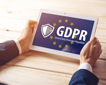 Two hands are holding a tablet with a screen on the GDPR and the EU flag in the background.