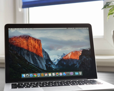 Macbook Pro with retina display on a table along with a smartphone.