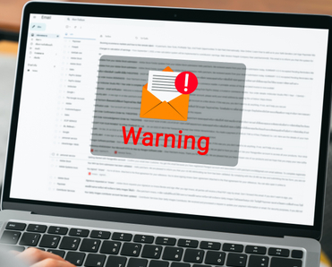 Laptop with email page open and a big envelope with mail warning sign on the screen