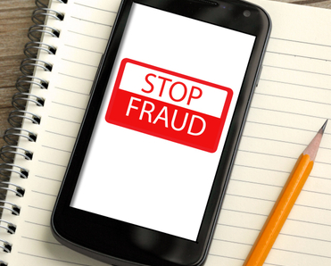 cellphone on top of notebook with yellow pencil on the side, on the screen in red and white &quot;stop fraud&quot; 