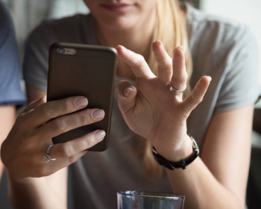 A woman holding her smartphone and scrolling through an app.