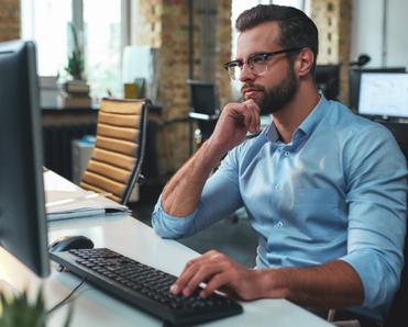 Side view of a man working on a computer in his office. 