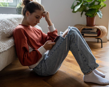 A teen girl sitting on the floor while using her smartphone. 