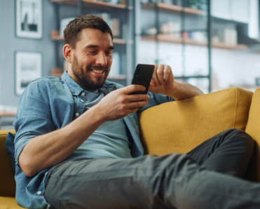 Man on couch smiling at phone