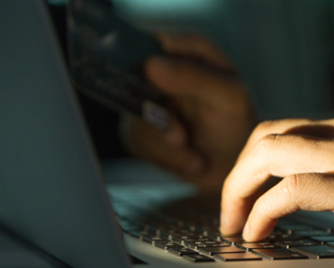 Hands on laptop keyboard with credit card