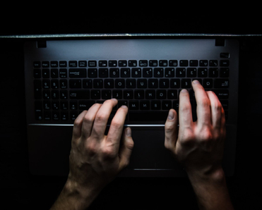 Hands on laptop in dark room