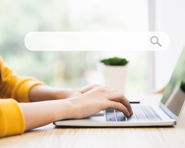 A pair of hands typing on a laptop with an abstract search bar in the foreground.