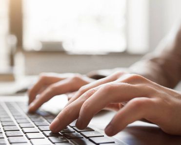 A pair of hands typing on a computer.