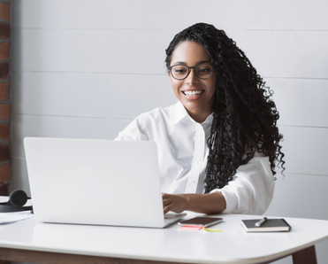 Woman types on her laptop at her desk.