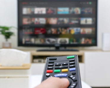 A remote is pointed toward a TV with Netflix on.