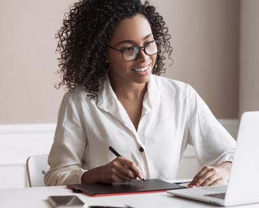 Woman holds a pen while staring at her laptop.
