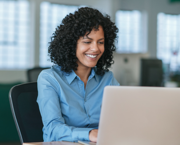 Woman smiles while staring down at her laptop.