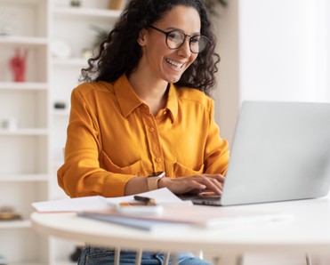 Woman smiles and types on her laptop in her office.