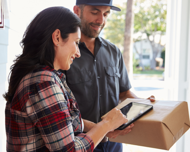 A woman signs for a package in her doorway.
